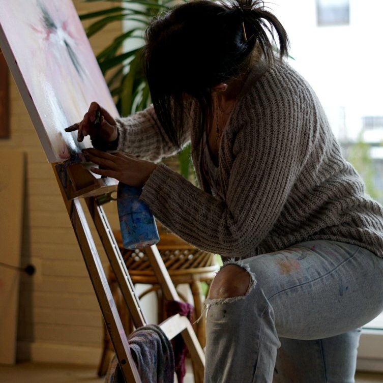 Serap Abdul malt an einer Leinwand abstrakte Kunst mit ihren Händen.